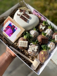 a person holding a box of chocolates and strawberries